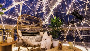 A cozy room with a wicker chair, a small table with a drink, and a telescope.