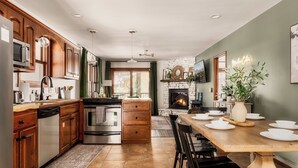 A modern kitchen with wooden cabinets, stainless steel appliances, and a dining area with a wooden table and chairs.