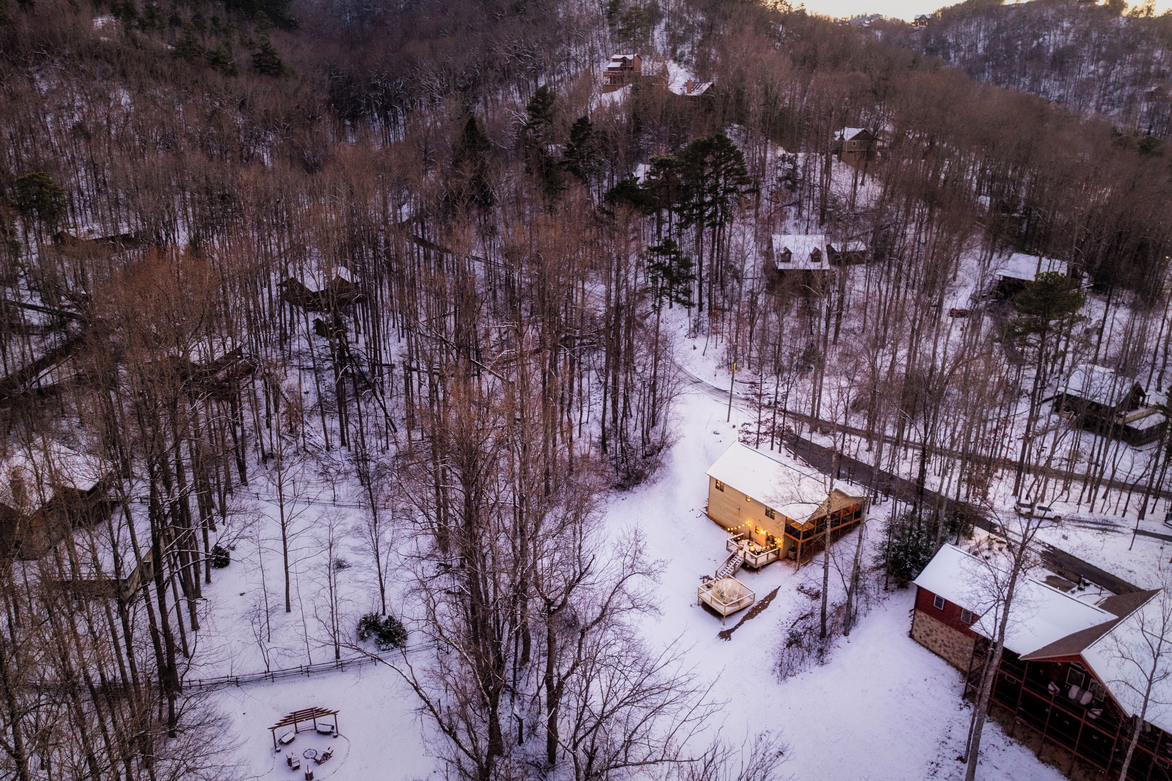 Eine Hütte, umgeben von einem verschneiten Wald, mit freiem Blick auf die Bäume und einer kleinen Terrasse.