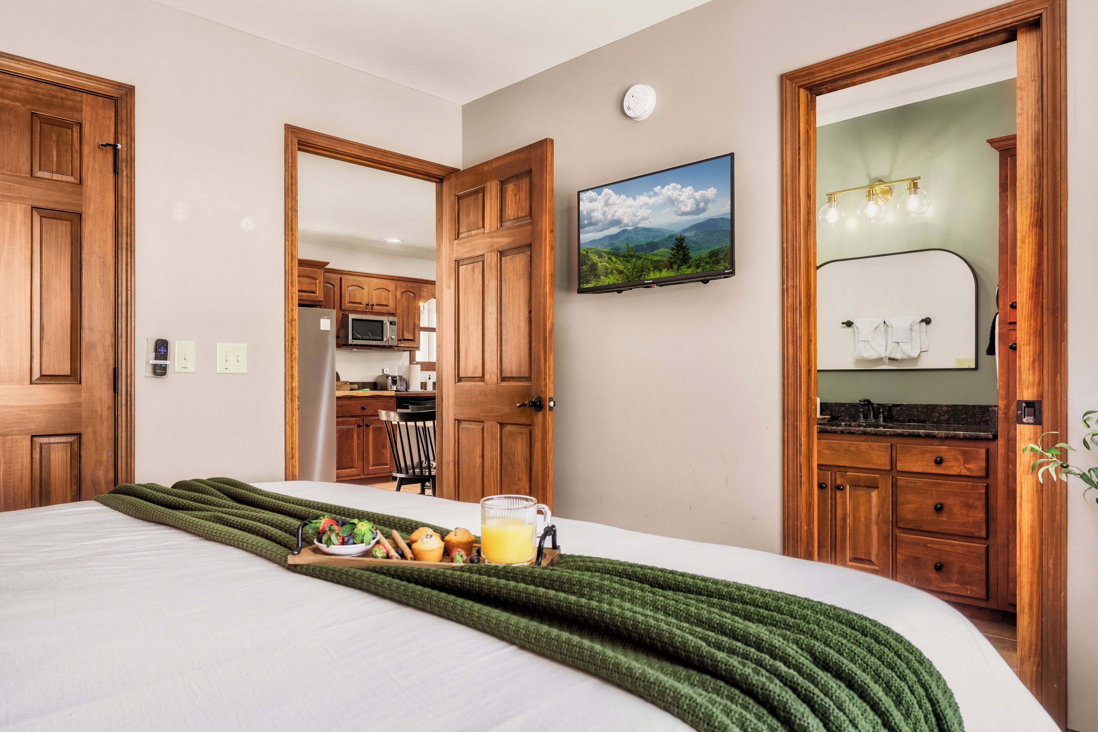 A hotel room with a bed, breakfast tray, and a view of the kitchen and dining area.