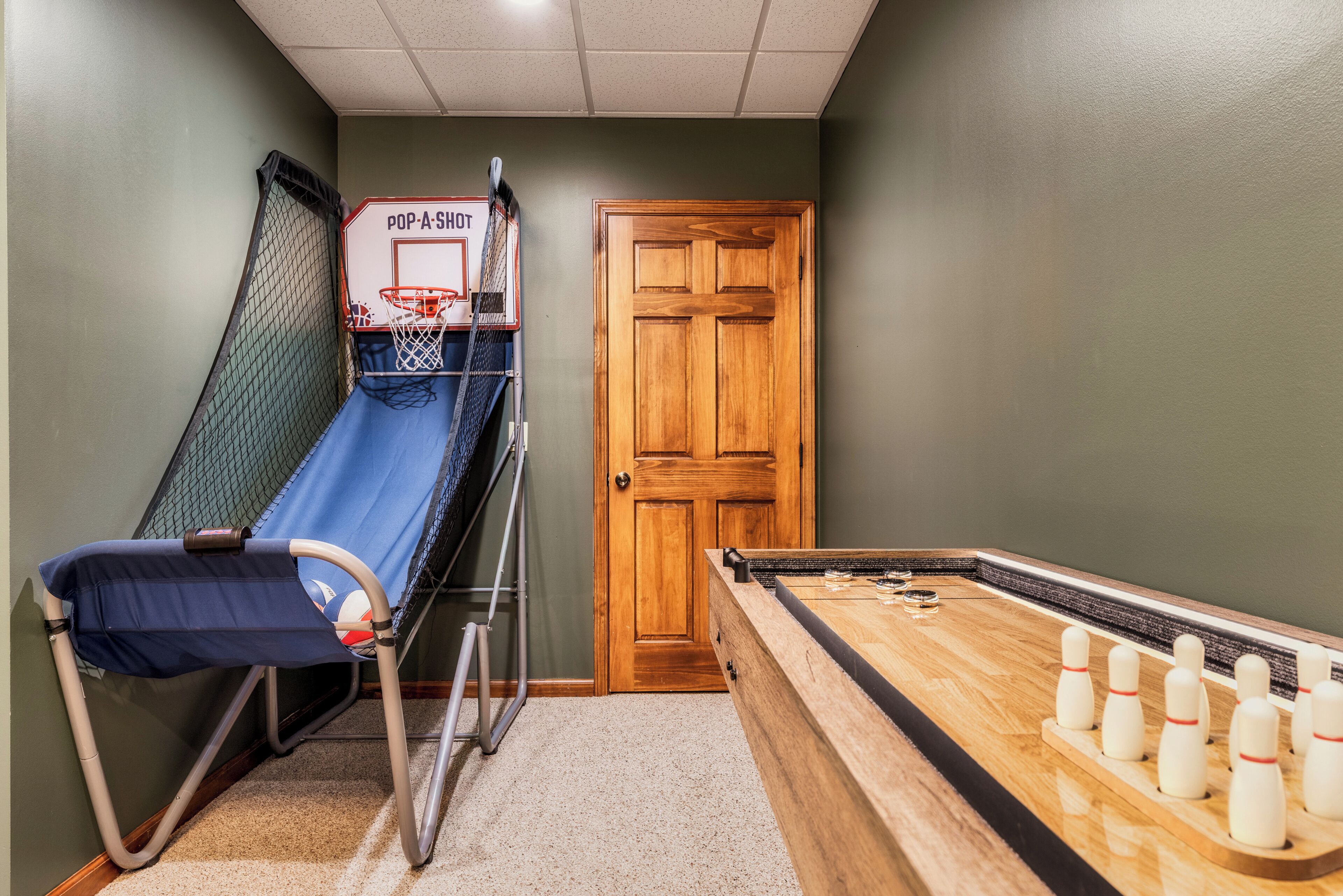 A room with a ping pong table, a small basketball hoop, and a door.