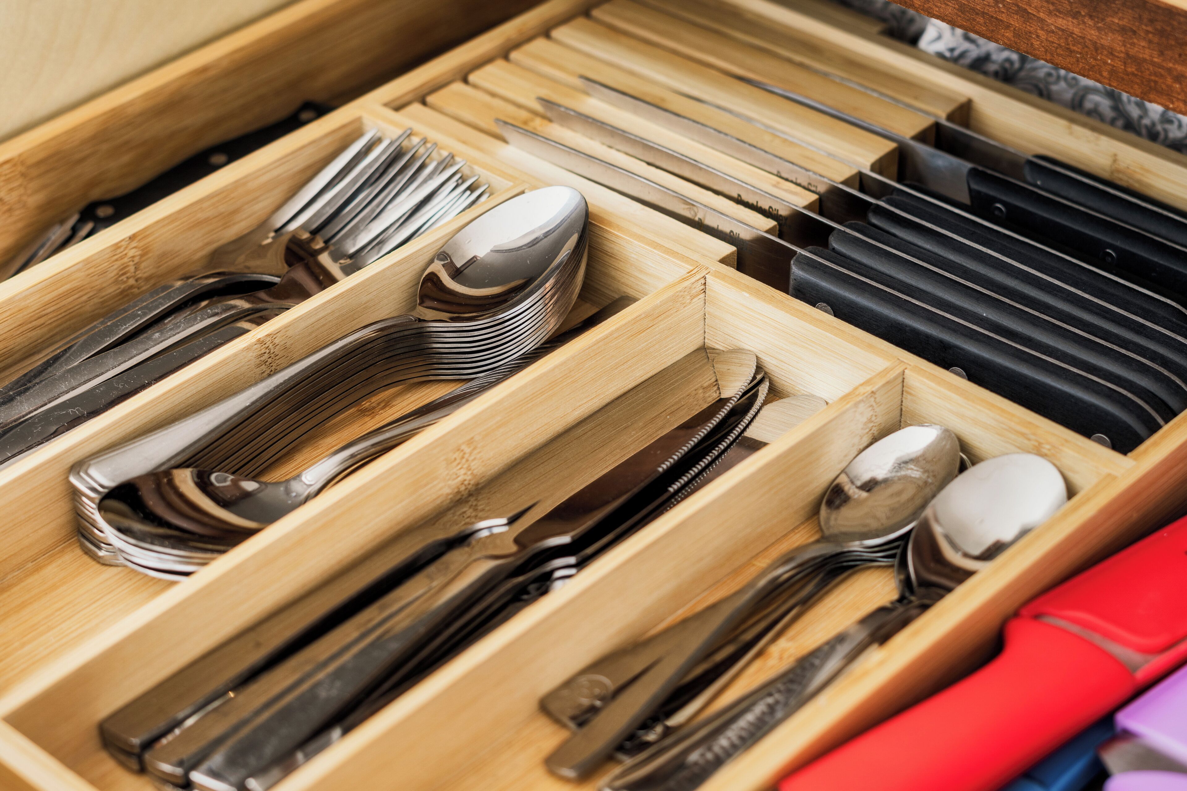A drawer with neatly organized cutlery including forks, spoons, and knives.