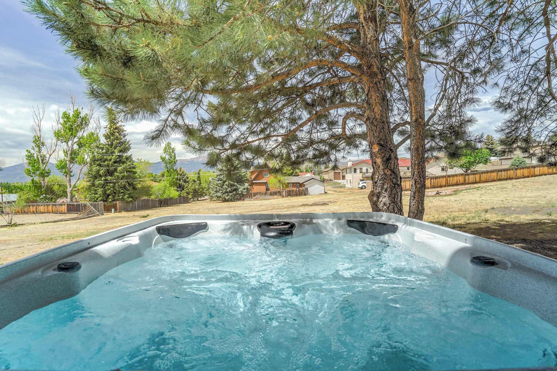 Un jacuzzi en un patio trasero con árboles y casas al fondo.