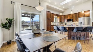 A modern kitchen with wooden cabinets, a central island, and a dining area with a table and chairs.