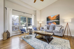 A living room with a sofa, chairs, a coffee table, a painting, and a lamp. - Foxwood Acres! Hot Tub & Deck Mountain Views Home (Colorado Springs)