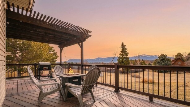 A wooden deck with a pergola, outdoor seating, and a view of mountains.