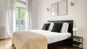 A bedroom with a bed, a nightstand, a lamp, and two wall-mounted light fixtures. - Blueground | Porte Saint Cloud, concierge (Paris)