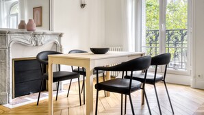 A dining area with a white table, black chairs, a black bowl, and a fireplace. - Blueground | Porte Saint Cloud, concierge (Paris)