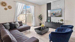 A modern living room with a sofa, armchairs, a coffee table, and a TV mounted on the wall. - Magical Getaway in the Best Location for a Perfect Vacation (Kissimmee)