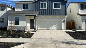 A two-story house with a garage, a stone foundation, and a well-maintained front yard. - NEW Smart Home w/ Massage Chair & King Bed (Lathrop)