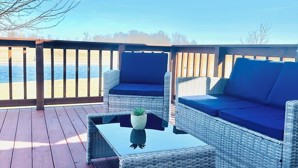 A deck with wicker furniture, a glass table, and a blue umbrella. - Homestead Stays, Heart of the area's top attractions (Oak Harbor)