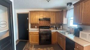 A kitchen with wooden cabinets, a stove, oven, microwave, and a sink. - Homestead Stays, Heart of the area's top attractions (Oak Harbor)