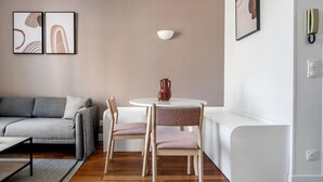 Ein modernes Wohnzimmer mit einem grauen Sofa, einem weißen runden Tisch und zwei Stühlen.