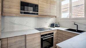 Eine moderne Küche mit Holzschränken, einer schwarzen Mikrowelle, einem eingebauten Ofen, einem Spülbecken und einem Fenster mit Blick auf das Dach.