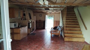 Une cuisine spacieuse avec des meubles en bois et un four à micro-ondes, un banc en bois dans le salon et un escalier en bois.