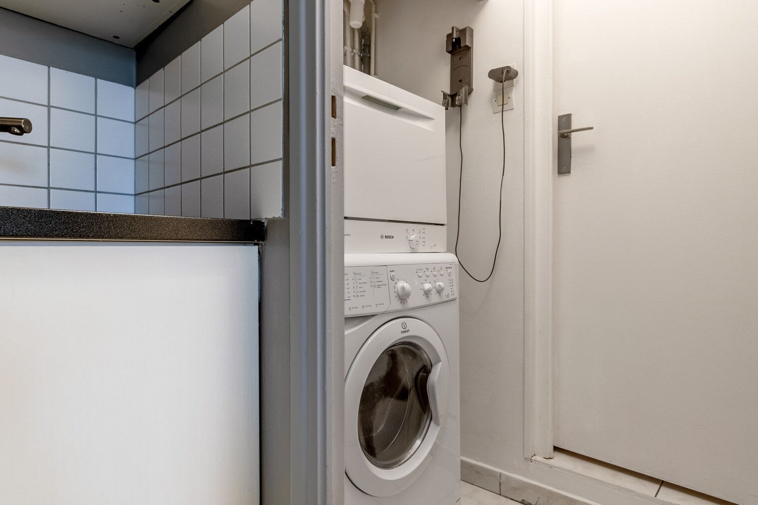 A compact laundry room with a front-loading washing machine, a dryer, and a shower.