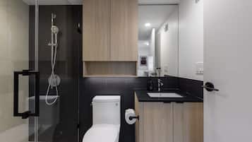 Un baño moderno con ducha envuelta en vidrio, inodoro y muebles de madera.