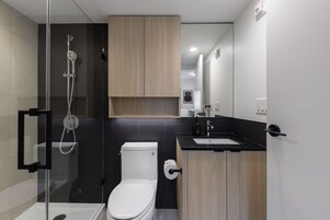 Un baño moderno con ducha envuelta en vidrio, inodoro y muebles de madera.