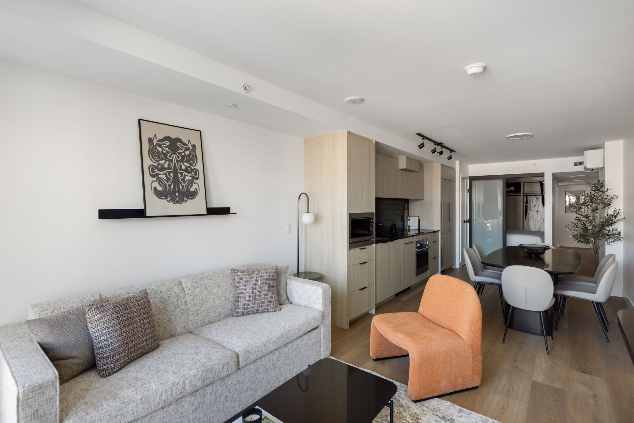 A modern living room with a sofa, a coffee table, and a dining area with chairs and a table.