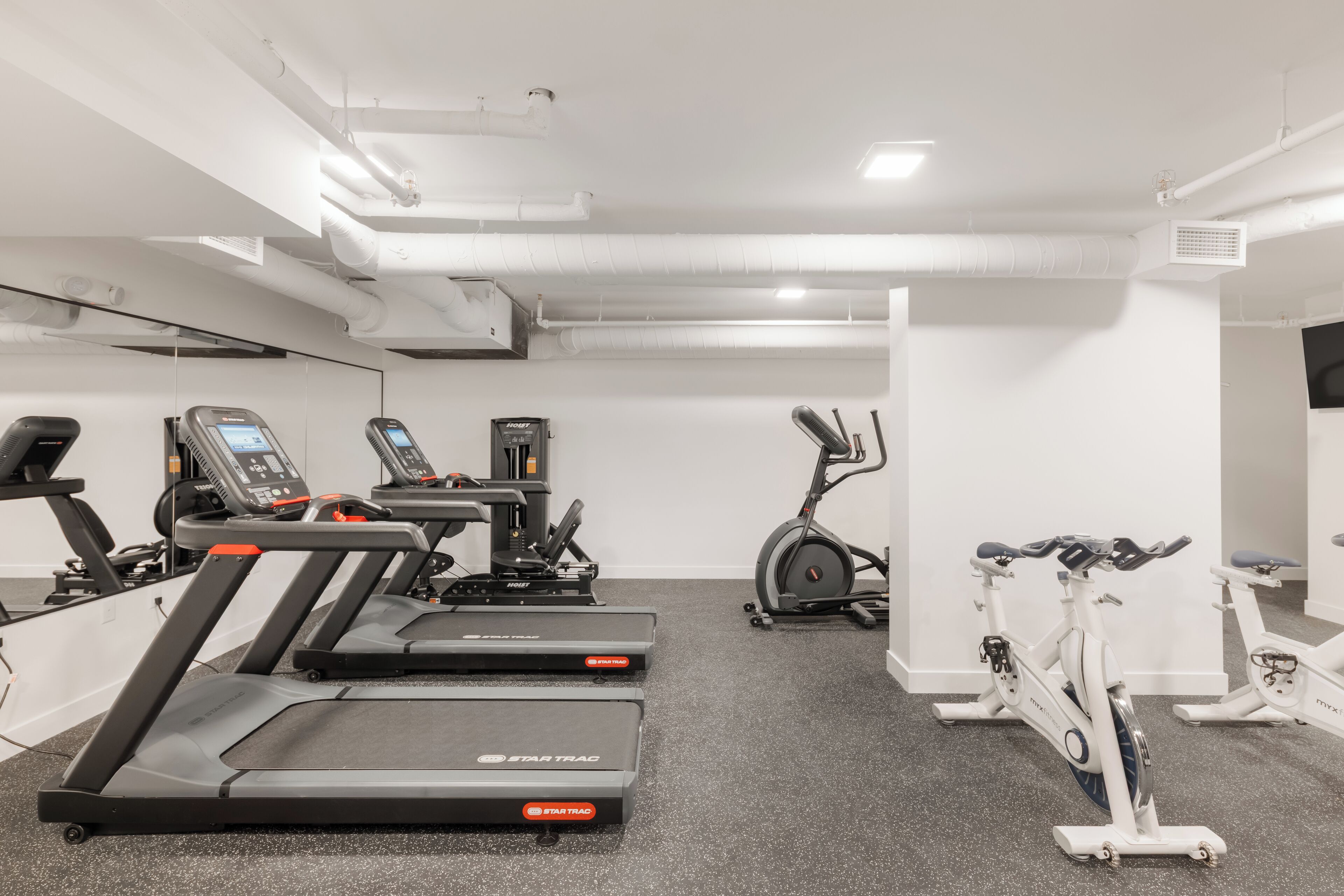 A gym with treadmills, an elliptical, and stationary bikes.