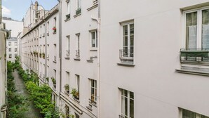 A narrow alleyway between buildings with balconies and windows. - Blueground | Grands Blvds, washer, nr shops (Paris)
