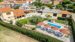 A residential area with a swimming pool, lounge chairs, and umbrellas.