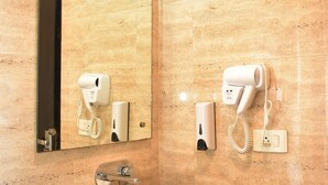 Ein Badezimmer mit einem weißen Waschbecken, einem Spiegel und zwei an der Wand befestigten Haartrocknern.