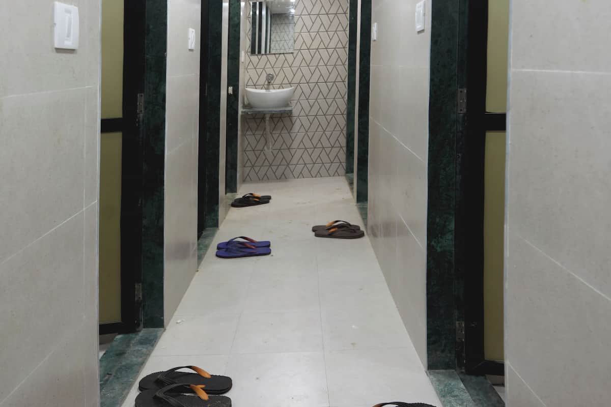A hallway with a tiled floor, a sink, and a mirror on the wall.