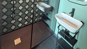 A modern bathroom with a geometric tile backsplash, a glass shower enclosure, and a white sink with a black faucet. - Volta 70 (Naples)