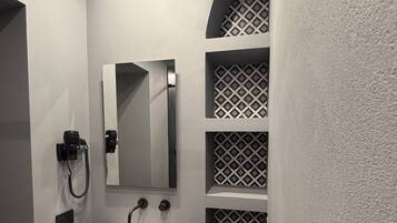 Un bagno moderno con un lavandino bianco, uno specchio e un asciugacapelli.