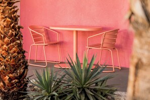 A round table with two chairs in front of a pink wall.