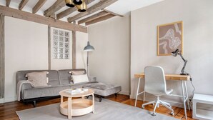 A modern living room with a grey sofa, a wooden coffee table, a desk with a chair, and a pendant light. - Blueground | Ternes, near shops, dining (Paris)