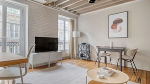 A modern living room with a TV, dining table, chairs, and a bookshelf. - Blueground | Ternes, near shops, dining (Paris)