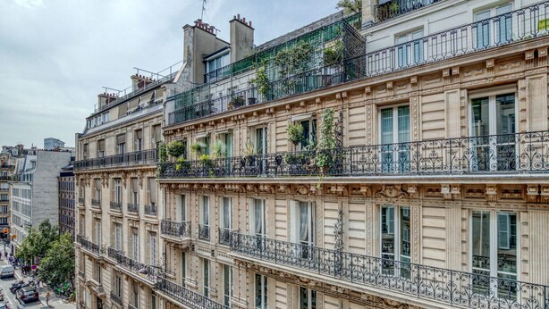 A multi-story building with balconies, large windows, and a street view. - Blueground | Ternes, near shops, dining (Paris)