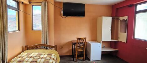 Una habitación de hotel con dos camas, un escritorio, una silla, un televisor y un armario.