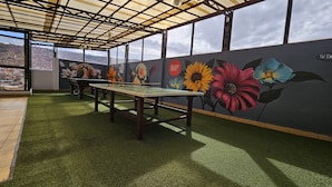 Una habitación con mesa de billar, césped artificial verde y un mural floral.
