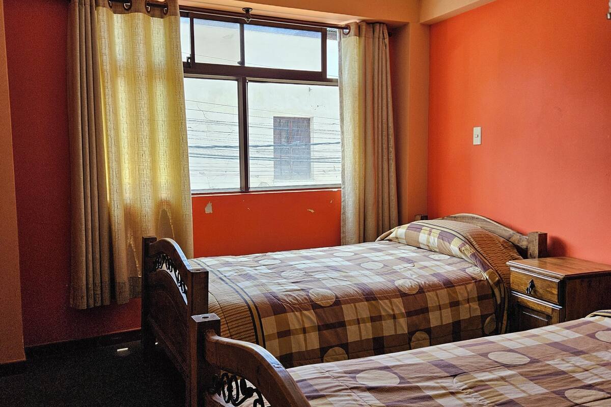 A room with two beds, a window with curtains, and a view of the water outside.