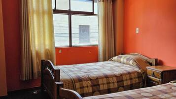 Una habitación con dos camas, una ventana con cortinas y vista al agua.