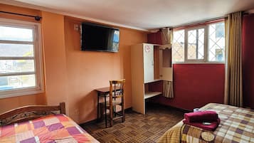 Habitación de hotel con dos camas, televisor, armario y ventana con vista a la ciudad.
