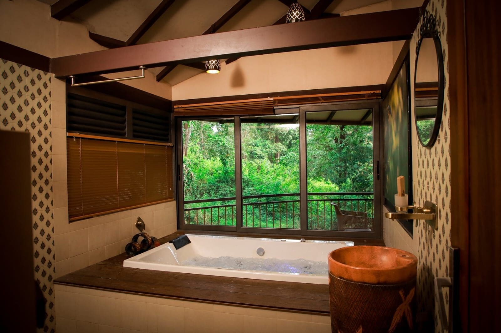 Ein Badezimmer mit einer großen Badewanne, einem Holzeimer und einem Fenster mit Blick auf Grünflächen.