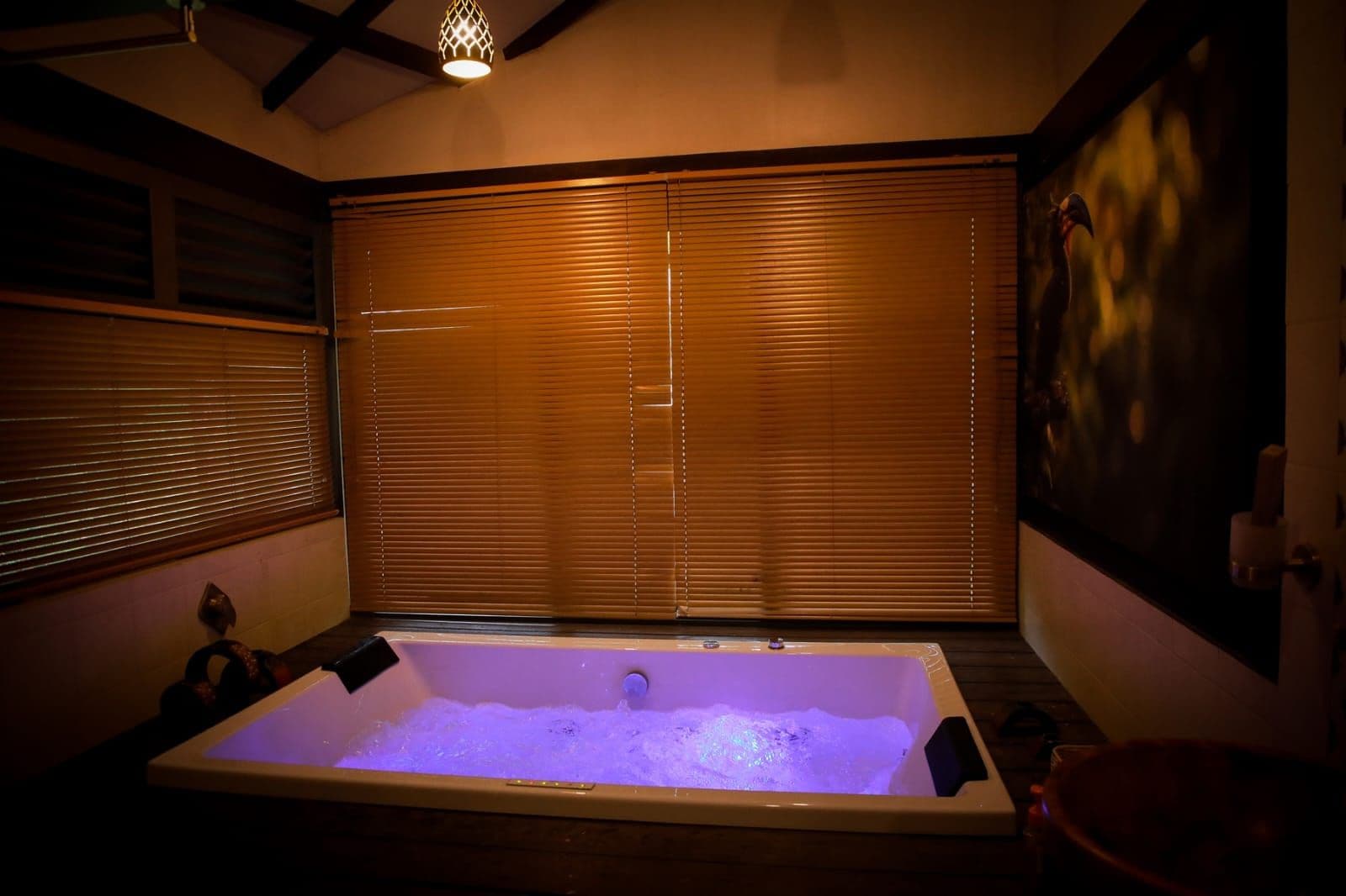 A spa room with a large bathtub, wooden blinds, and a wall-mounted heater.