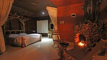 Una habitación acogedora con una cama, una mesa con fuego y una pared de piedra.