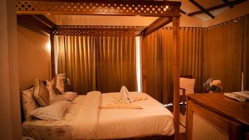 Una cama con dosel, una mesita de noche con un teléfono y un florero con flores.