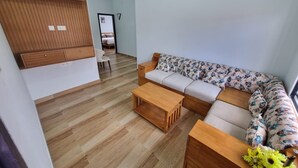 Un salon moderne avec un banc en bois, un canapé recouvert d’un tissu à motifs floraux et une table basse en bois.