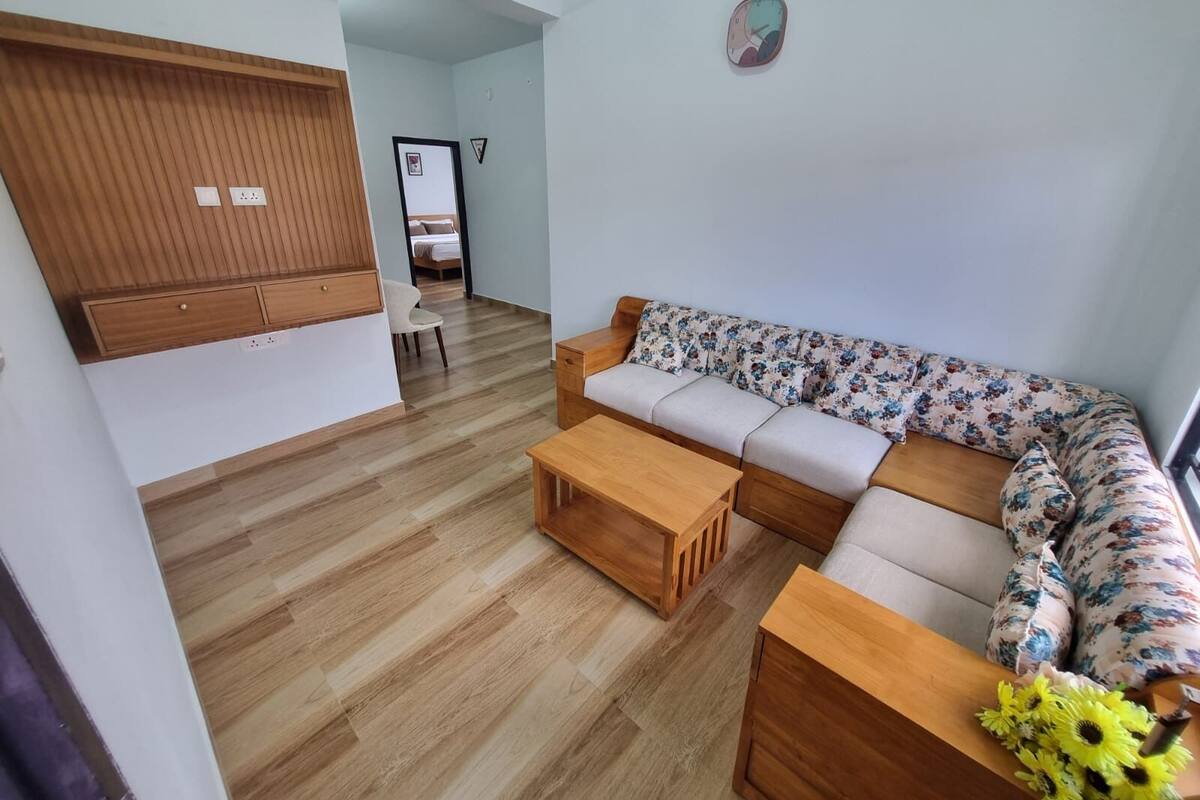 A modern living room with a wooden bench, a sofa with floral upholstery, and a wooden coffee table.