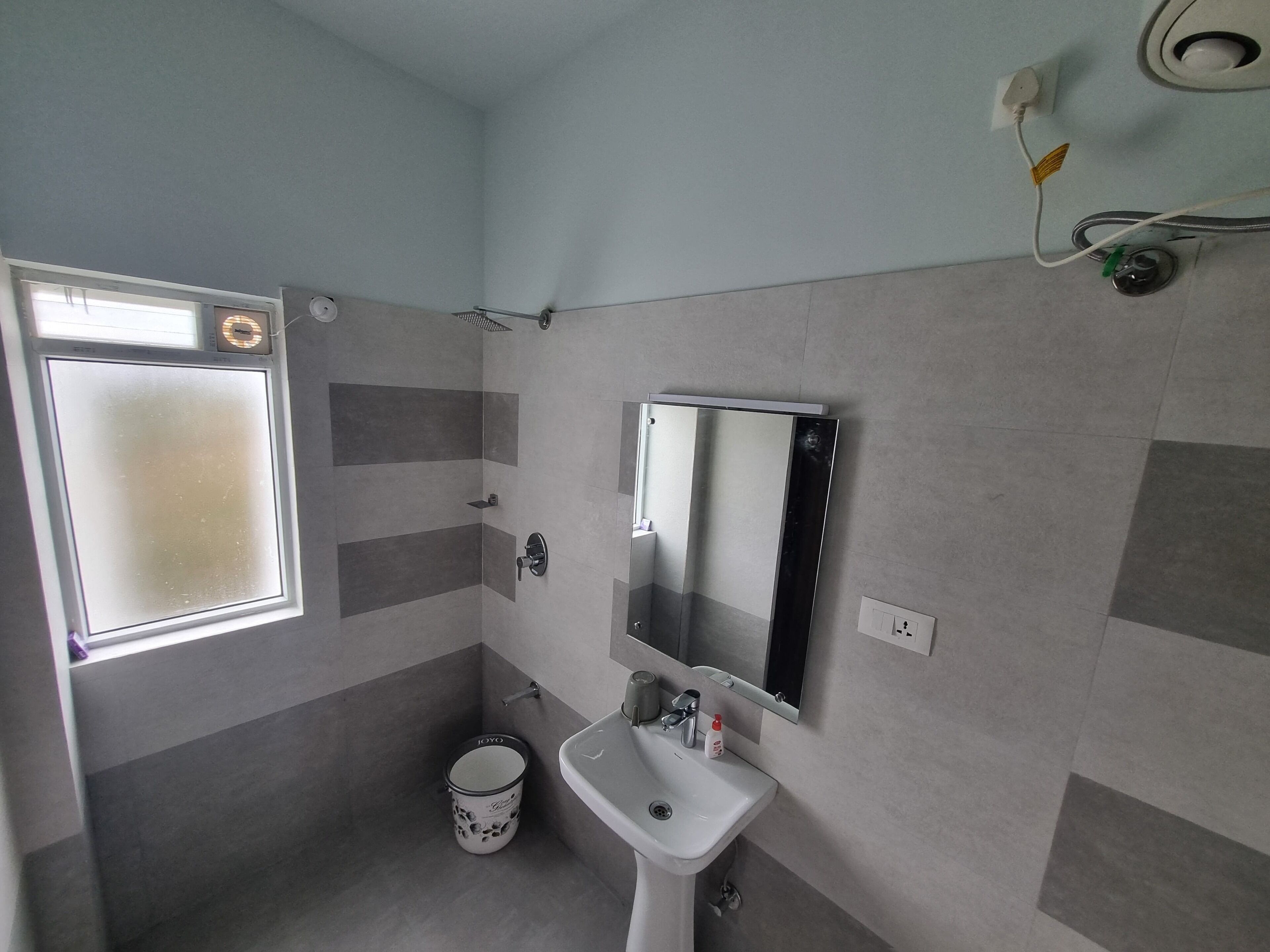 A bathroom with a window, a sink, a mirror, and a toilet.