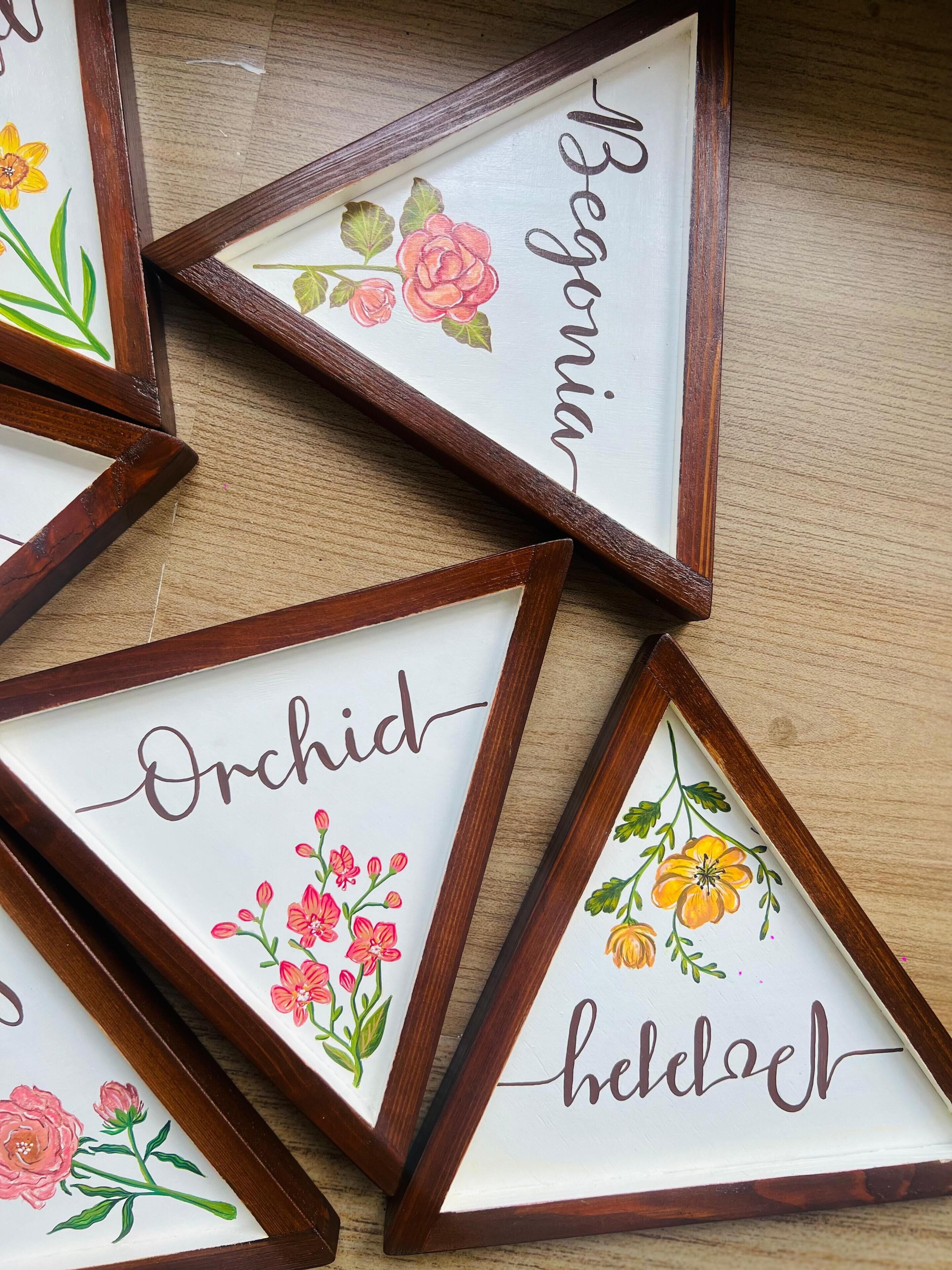 A collection of triangular picture frames with floral designs and names.