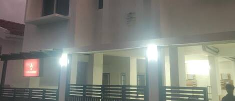 Un edificio de dos pisos con entrada protegida por un portón y una motocicleta estacionada afuera.