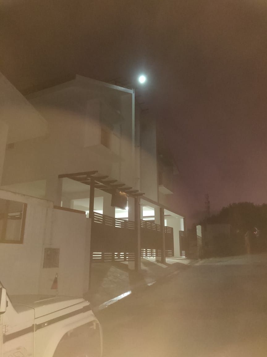 A modern building with a flat roof and large windows, a streetlight, and a parked vehicle.
