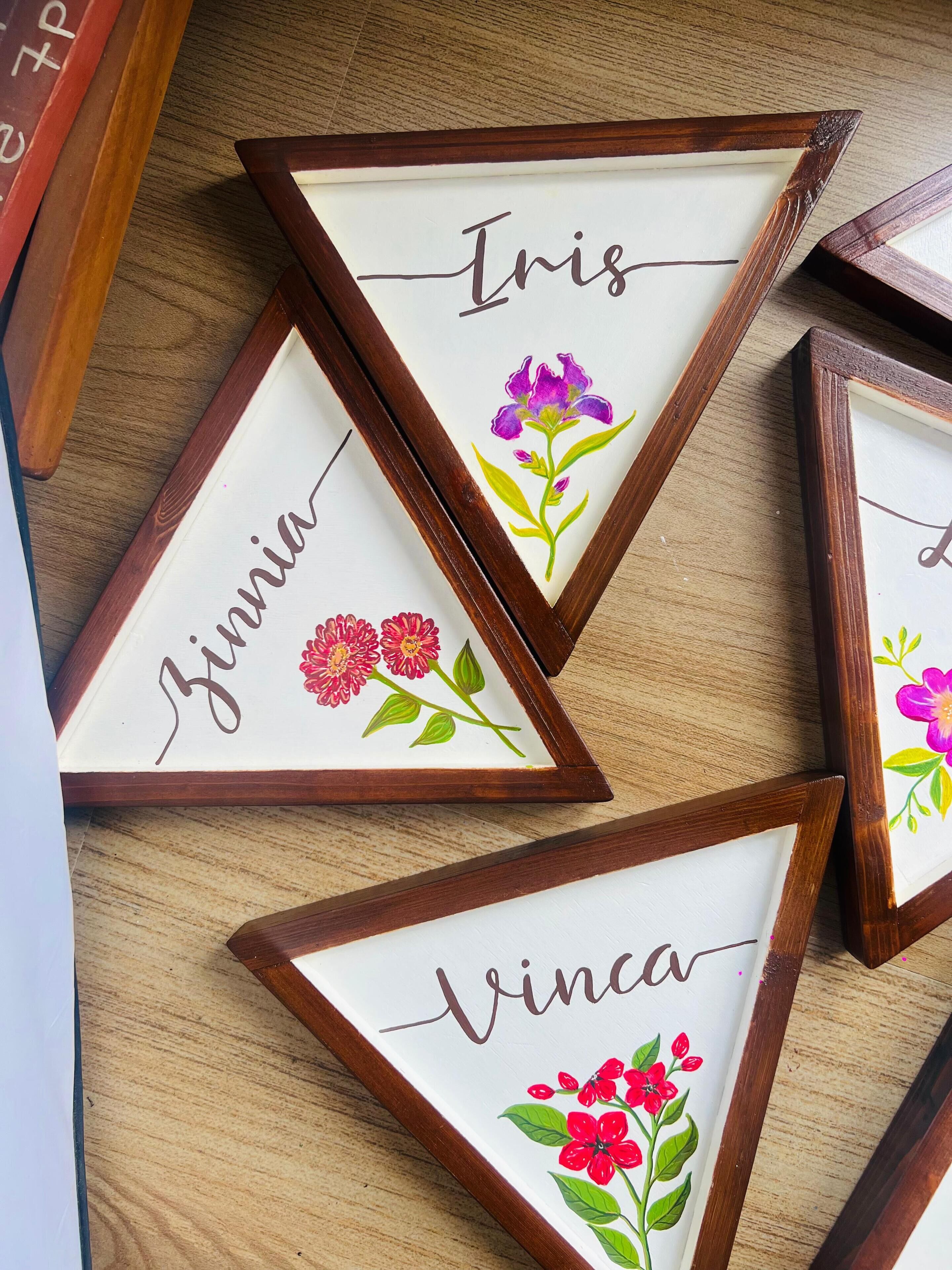 Three name-framed picture frames with floral designs on a wooden surface.